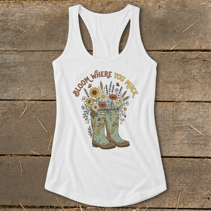 White tank top with green boots and flowers, "Bloom Where You Muck" text.