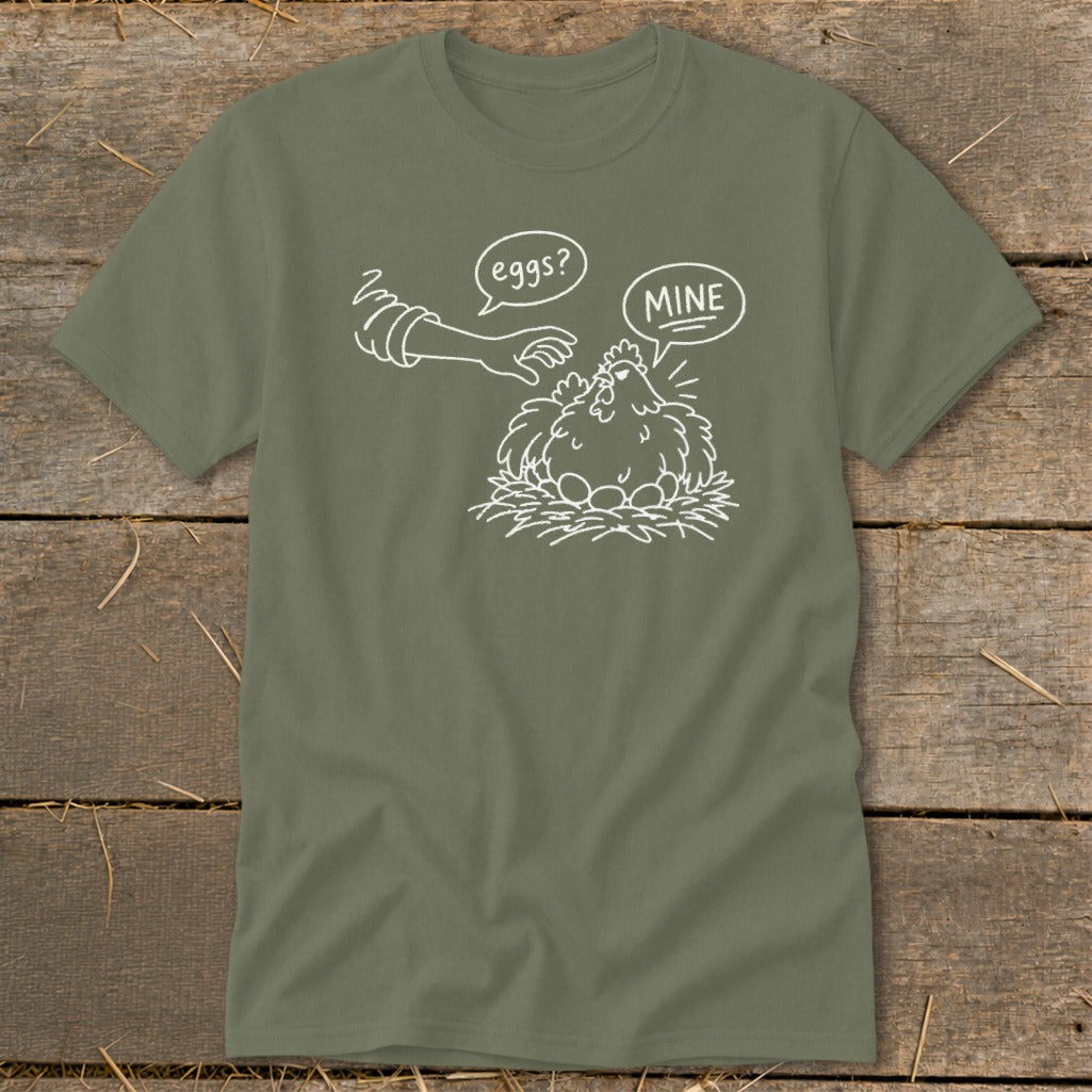 Olive green t-shirt with a line drawing of a chicken and eggs, hand saying "eggs?", chicken saying "MINE".