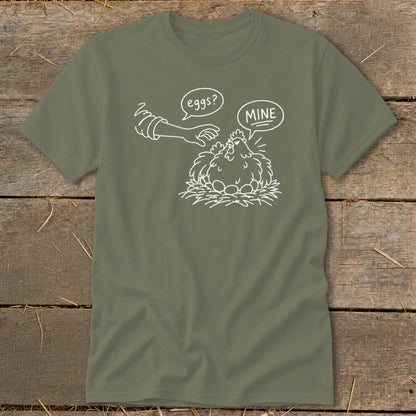 Olive green t-shirt with a line drawing of a chicken and eggs, hand saying "eggs?", chicken saying "MINE".