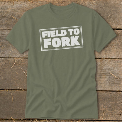 An olive green t-shirt with white distressed text reading "FIELD TO FORK" inside a double-lined rectangular box.