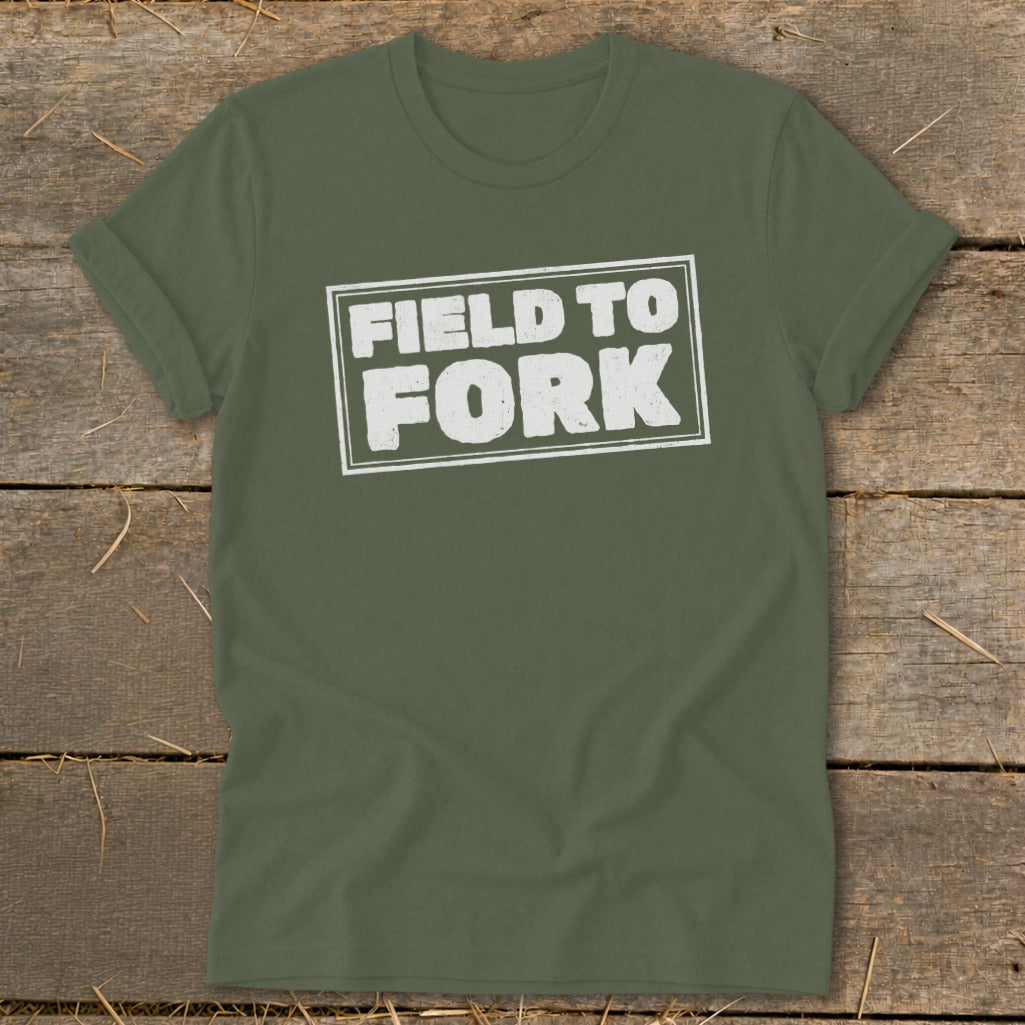 Olive green crewneck t-shirt with rolled sleeves displaying the white distressed text FIELD TO FORK centered on a wooden background.