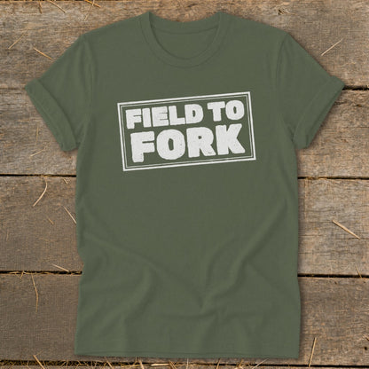 Olive green crewneck t-shirt with rolled sleeves displaying the white distressed text FIELD TO FORK centered on a wooden background.