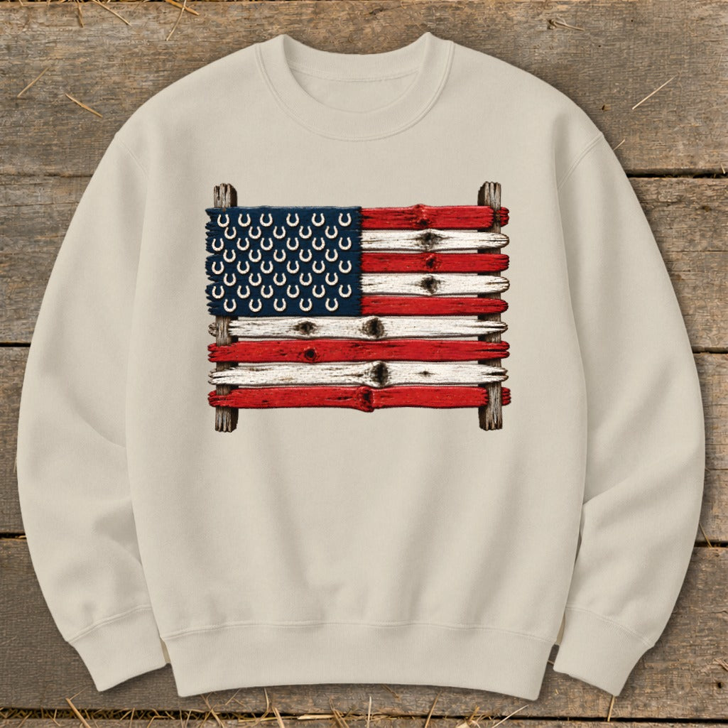 Beige crewneck sweatshirt featuring a rustic American flag made of weathered wood and horseshoes.