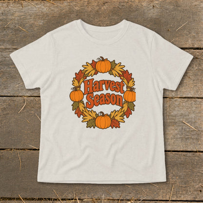 T-shirt with a circular harvest wreath design featuring pumpkins and autumn leaves.
