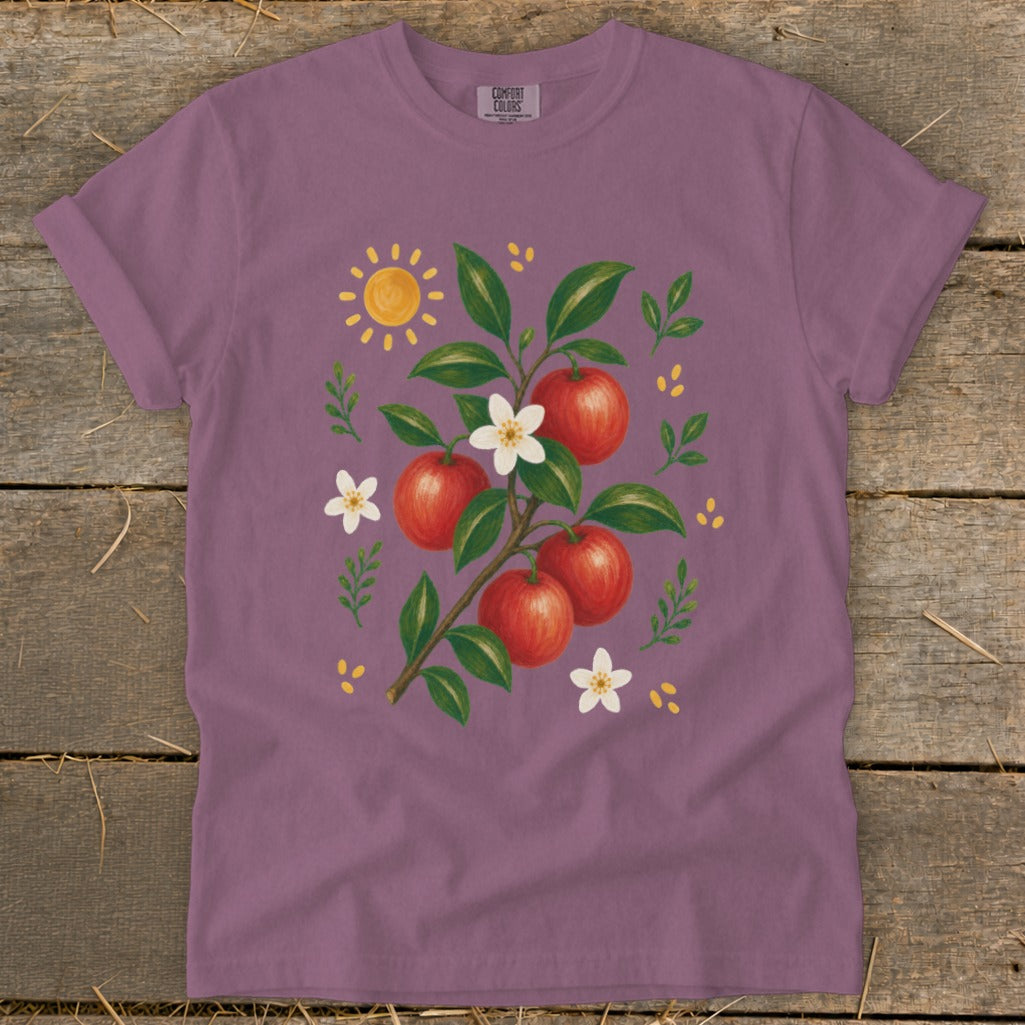 Purple t-shirt with a watercolor print of apples on a branch, flowers, and a sun.