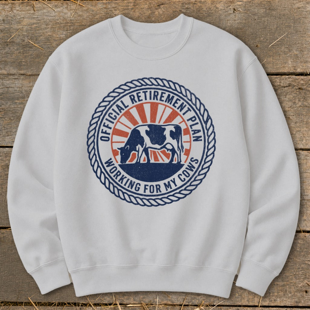 White sweatshirt with a circular graphic of a cow and "Official Retirement Plan Working for My Cows" text.