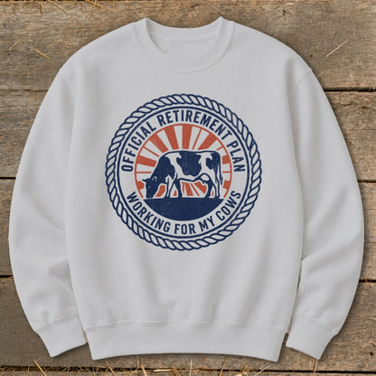 White sweatshirt with a circular graphic of a cow and "Official Retirement Plan Working for My Cows" text.