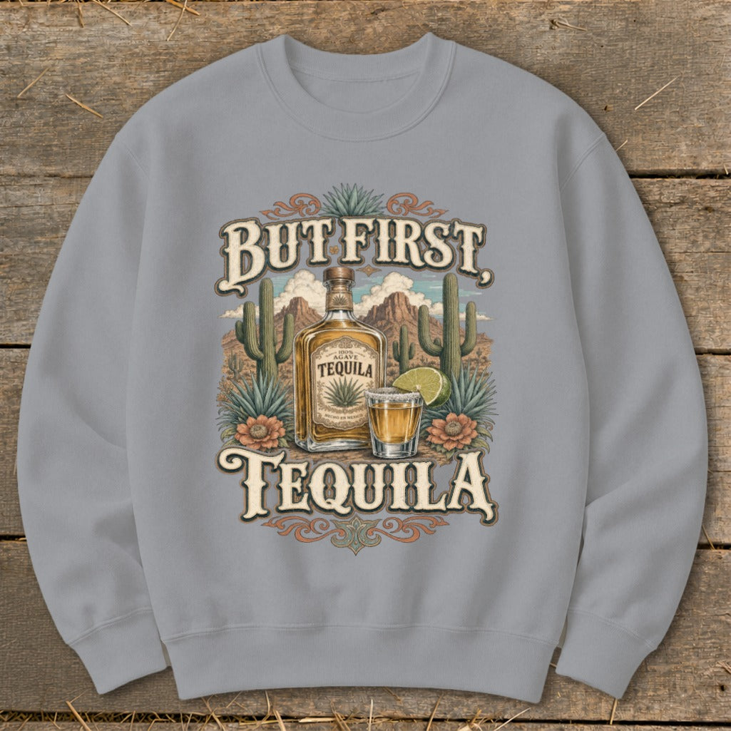 Sweatshirt with "But First Tequila" text, tequila bottle, shot, and desert landscape.