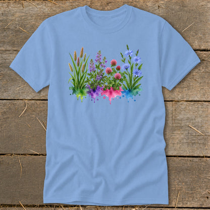 A light blue t-shirt printed with a watercolor botanical illustration of wildflowers over colorful paint splatters.