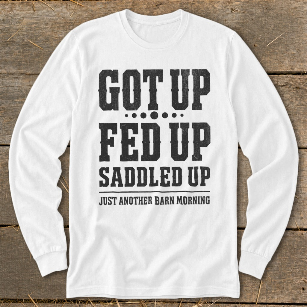 White long-sleeve shirt with black text reading "GOT UP FED UP SADDLED UP JUST ANOTHER BARN MORNING".