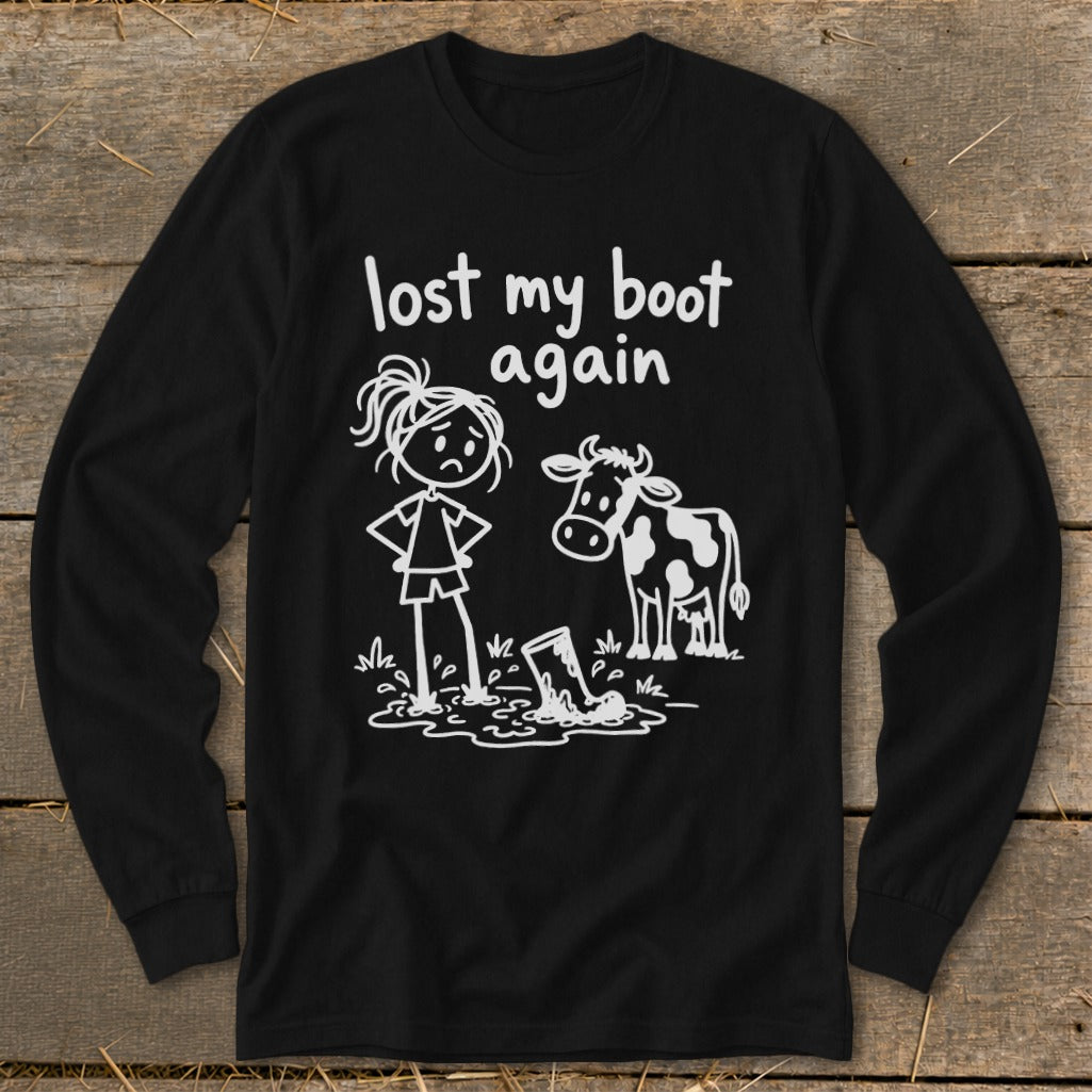 A black long-sleeve t-shirt features a white stick-figure graphic of a girl standing in mud with a cow, captioned "lost my boot again."