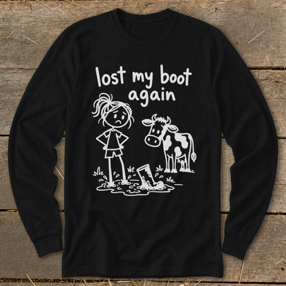 A black long-sleeve t-shirt features a white stick-figure graphic of a girl standing in mud with a cow, captioned "lost my boot again."
