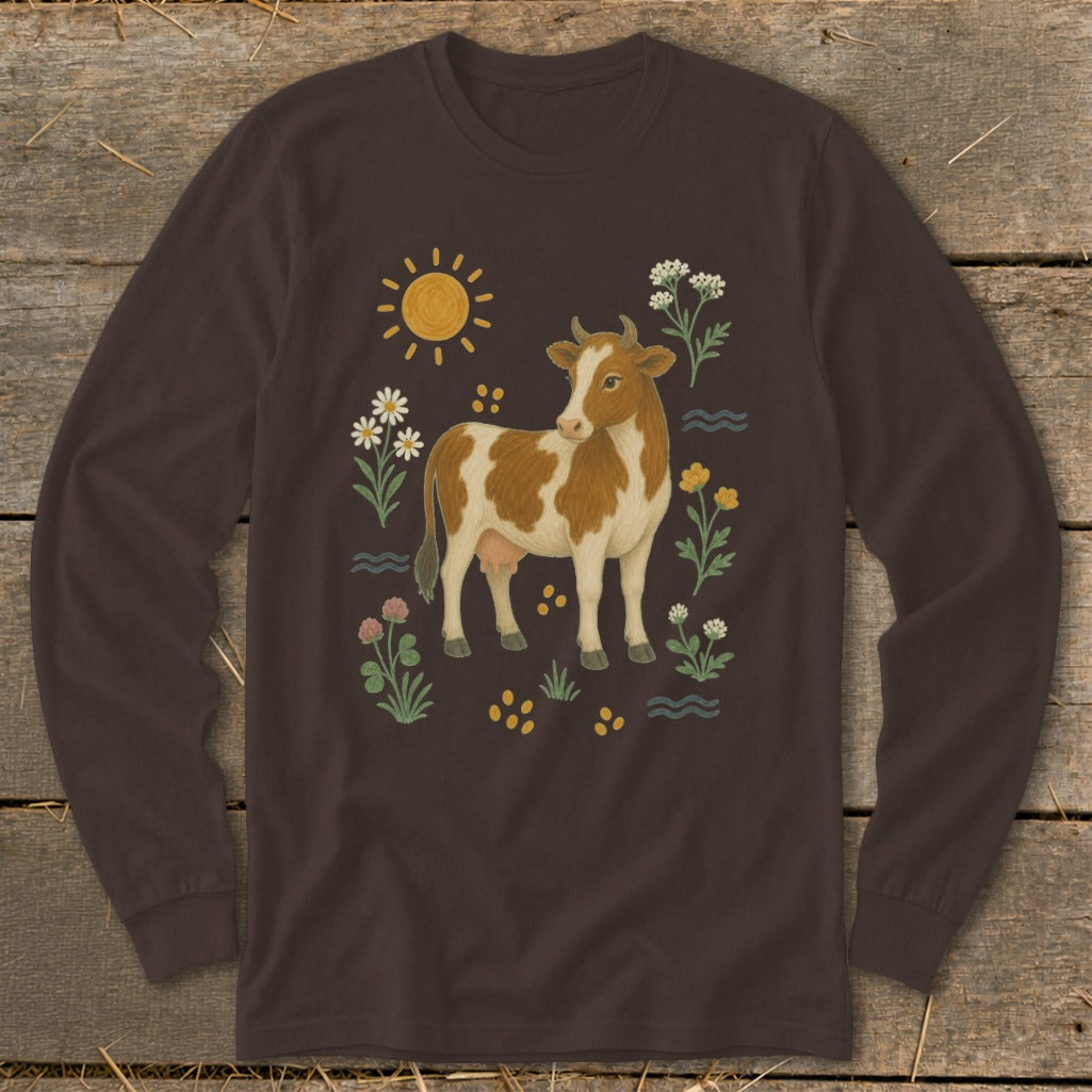 Brown long-sleeve shirt with a brown and white cow surrounded by flowers, sun, and water.