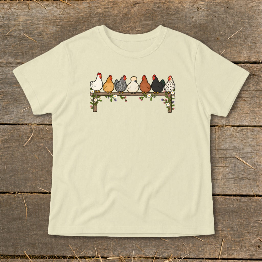 Cream-colored t-shirt with an illustration of seven colorful chickens perched on a flower-decorated wooden fence.