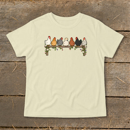 Cream-colored t-shirt with an illustration of seven colorful chickens perched on a flower-decorated wooden fence.