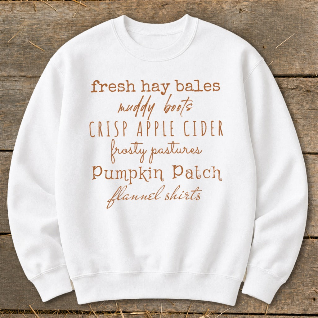 White sweatshirt with autumn-themed text: fresh hay bales, muddy boots, crisp apple cider, frosty pastures, pumpkin patch, flannel shirts.