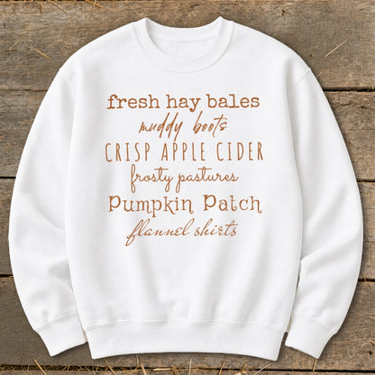 White sweatshirt with autumn-themed text: fresh hay bales, muddy boots, crisp apple cider, frosty pastures, pumpkin patch, flannel shirts.