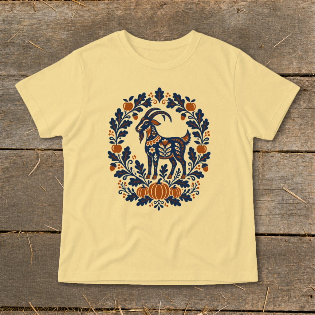 Light yellow short-sleeve t-shirt with a blue and orange folk art goat and autumn wreath graphic centered on the chest.