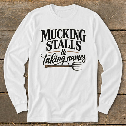 White long sleeve shirt with "Mucking Stalls & Taking Names" text and a pitchfork graphic.
