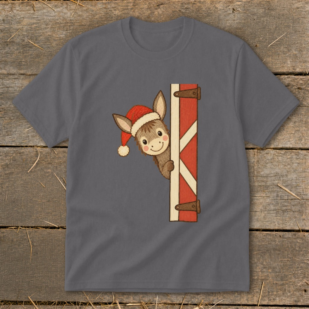 Donkey wearing Santa hat peeking from behind a rustic barn door on a grey t-shirt.