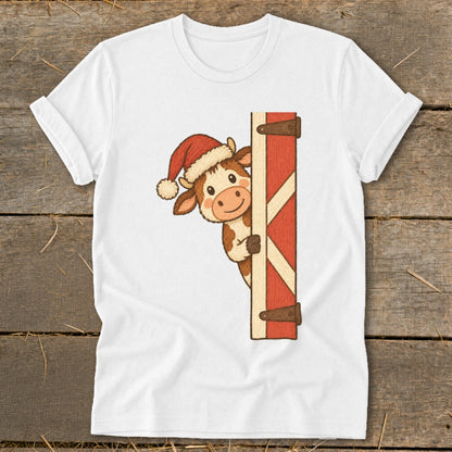 White t-shirt with a cartoon cow wearing a Santa hat peeking behind a barn door.
