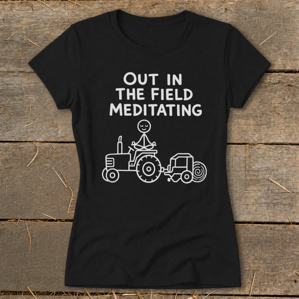 Black t-shirt with "Out in the Field Meditating" text and a stick figure meditating on a tractor.