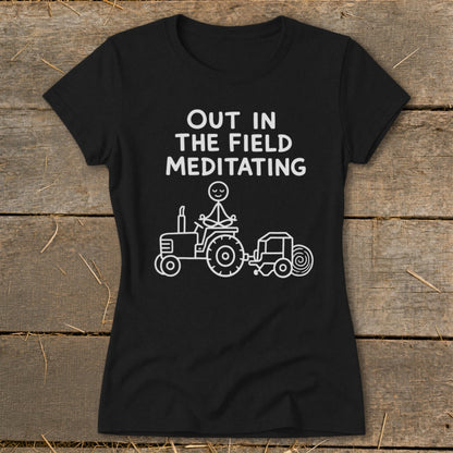 Black t-shirt with "Out in the Field Meditating" text and a stick figure meditating on a tractor.
