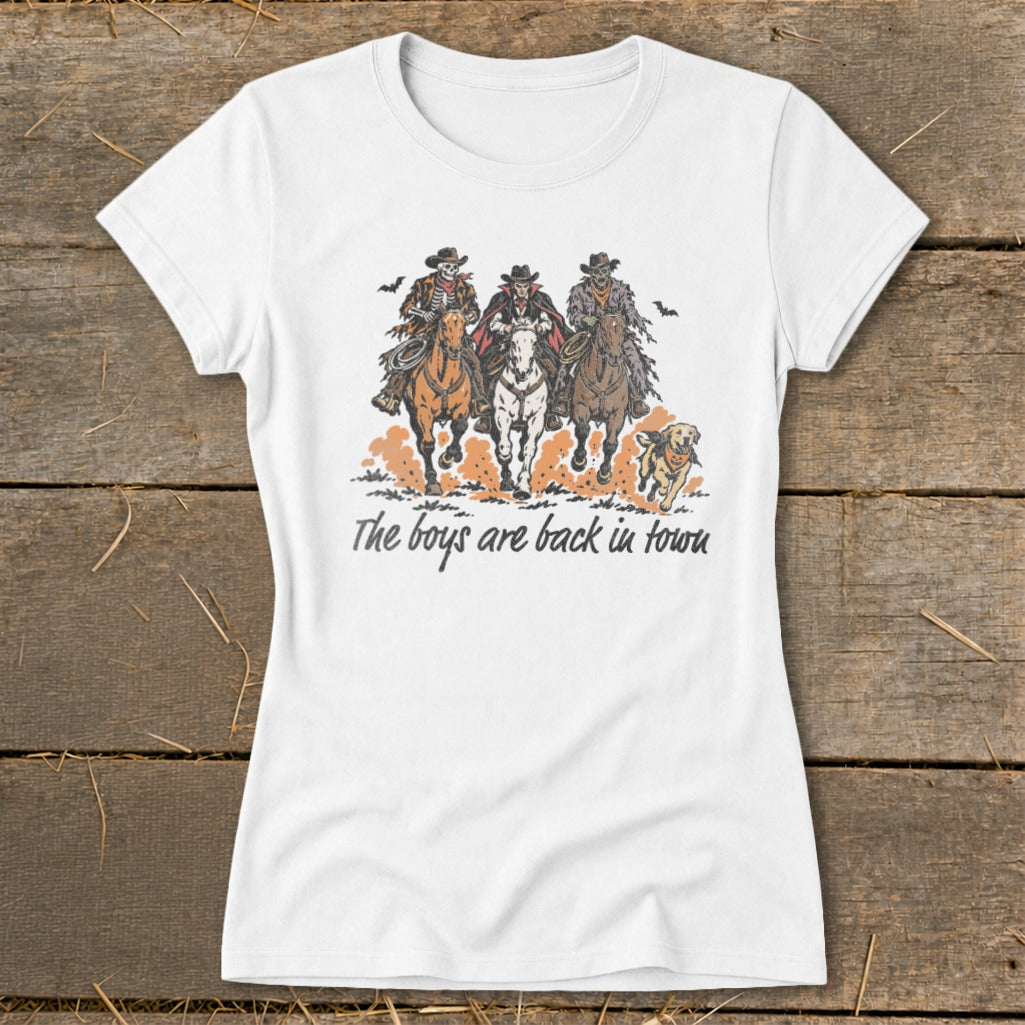 White t-shirt with graphic of three cowboys, one skeleton, and a dog, reading "The boys are back in town".