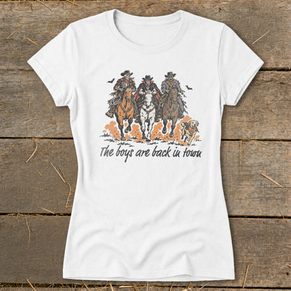 White t-shirt with graphic of three cowboys, one skeleton, and a dog, reading "The boys are back in town".