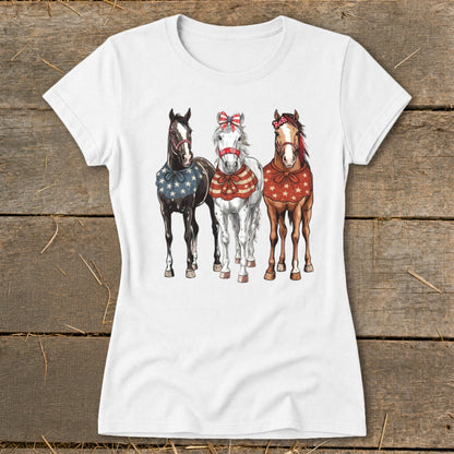 Three horses, black, white, and brown, wear patriotic bandanas and bows.
