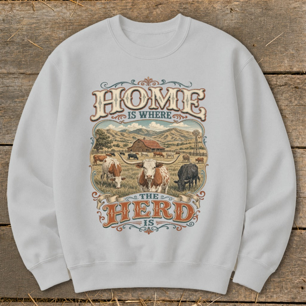 Sweatshirt with graphic featuring cows, a barn, and the text "HOME IS WHERE THE HERD IS".