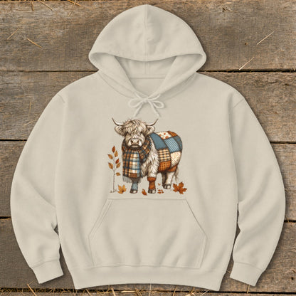Cream hoodie with Highland cow graphic wearing a plaid scarf and patchwork blanket.