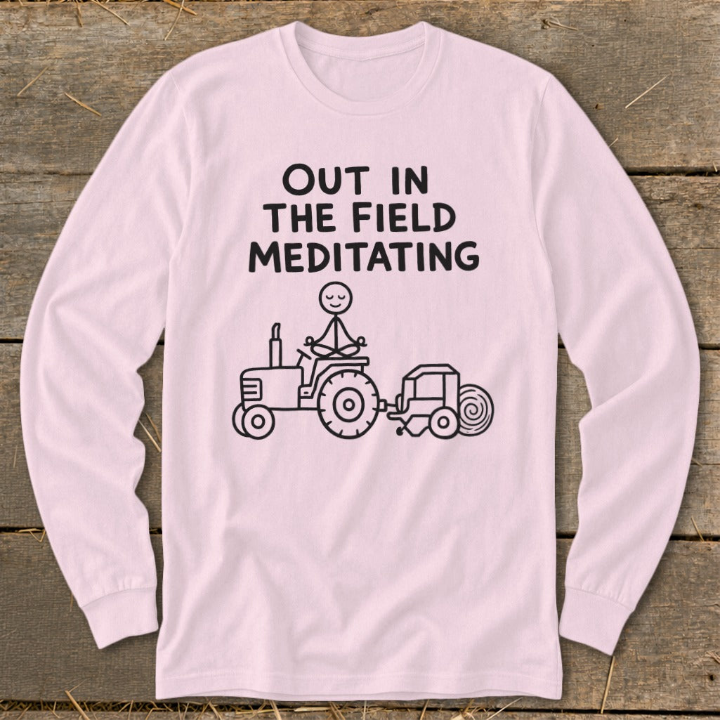 Long-sleeve pink shirt with "Out in the Field Meditating" text and stick figure meditating on a tractor.