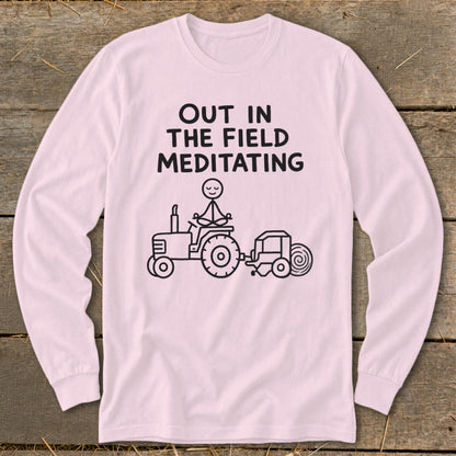 Long-sleeve pink shirt with "Out in the Field Meditating" text and stick figure meditating on a tractor.