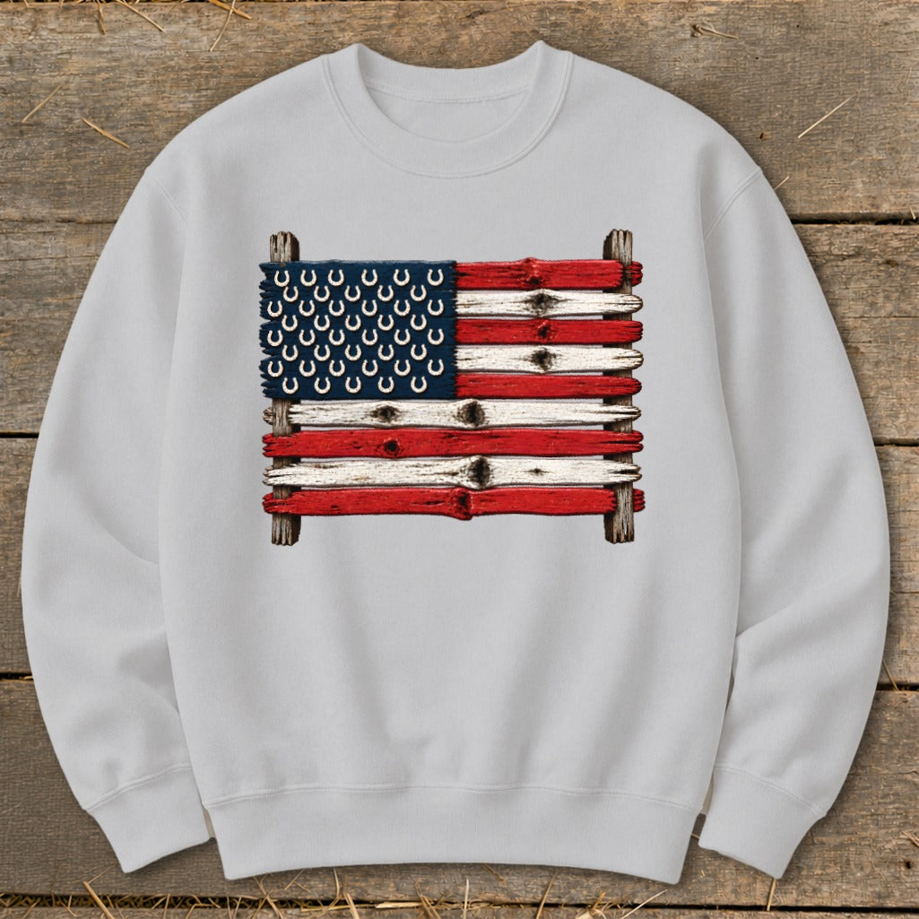 Light gray crewneck sweatshirt featuring a rustic American flag graphic made of painted wooden planks and horseshoes.