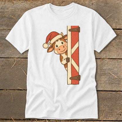 White t-shirt with a cartoon cow wearing a Santa hat peeking from behind a red barn door.