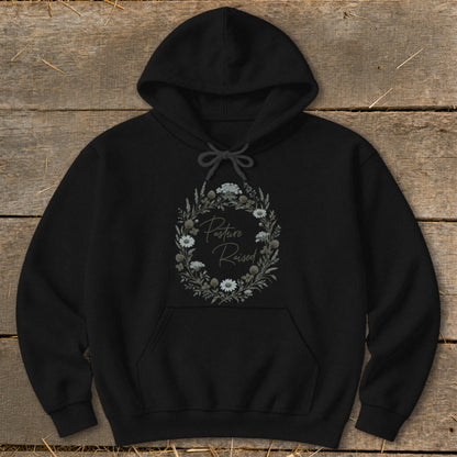 Black hoodie with oval floral wreath and "Pasture Raised" text.
