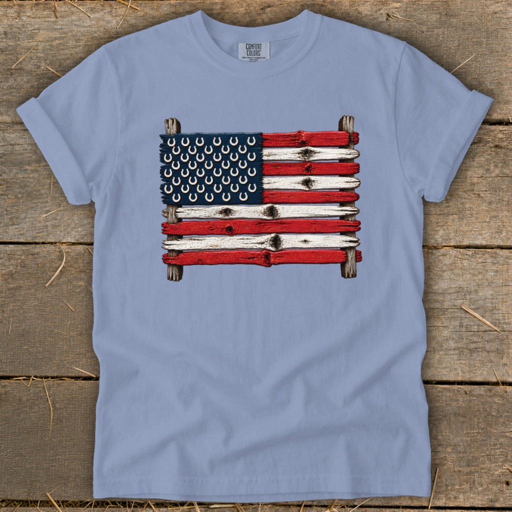 Light blue t-shirt featuring an American flag made of painted wooden planks and horseshoes.