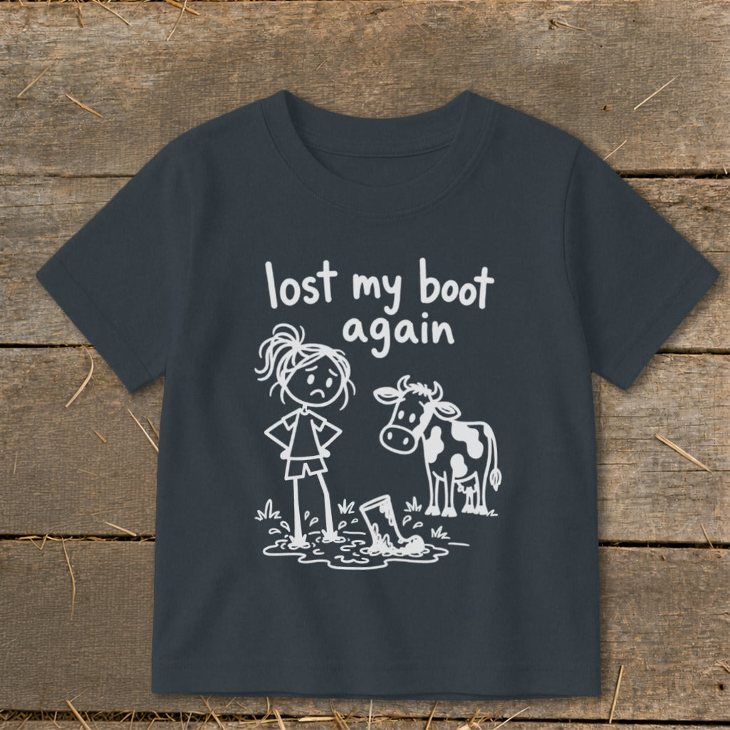 Dark grey t-shirt featuring a white graphic of a sad girl standing next to a cow and a muddy boot, with the text "lost my boot again."