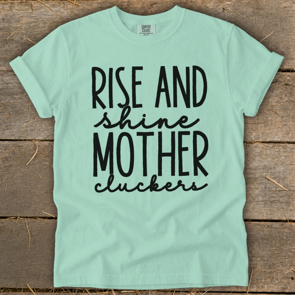Mint green t-shirt with black text "Rise and shine mother cluckers."