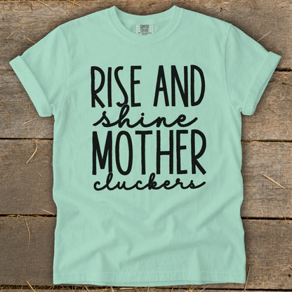 Mint green t-shirt with black text "Rise and shine mother cluckers."