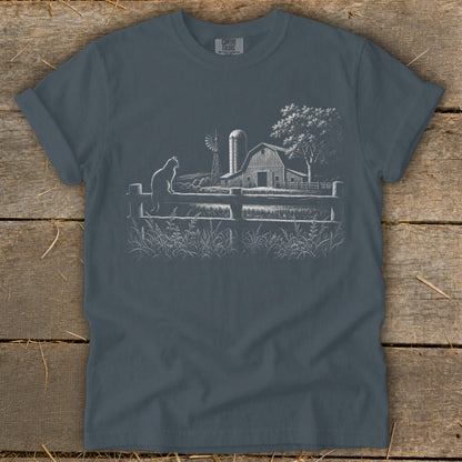 T-shirt with white line art of a farm scene: cat, barn, windmill, fence, and tree.