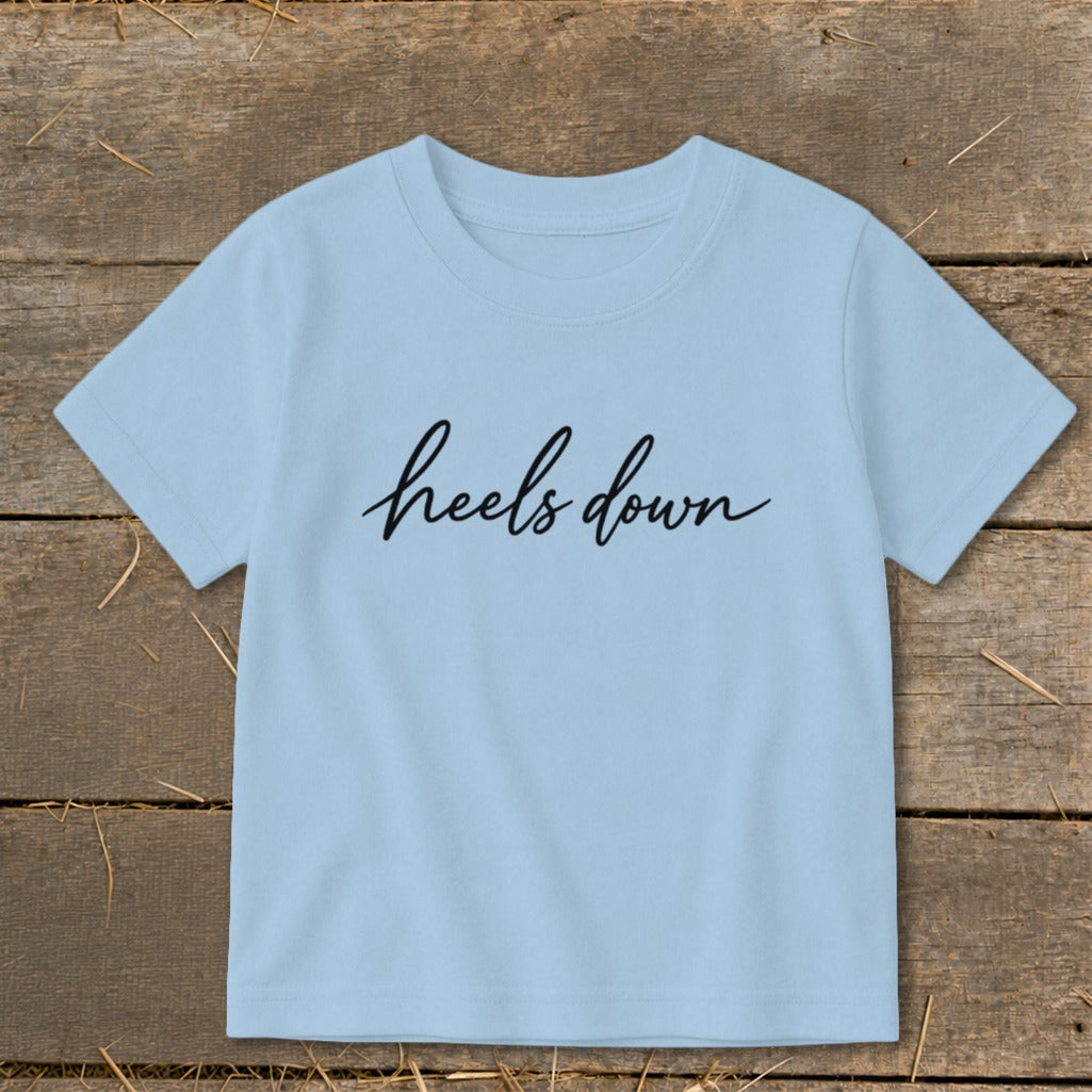 Light blue t-shirt with black cursive text reading "heels down".