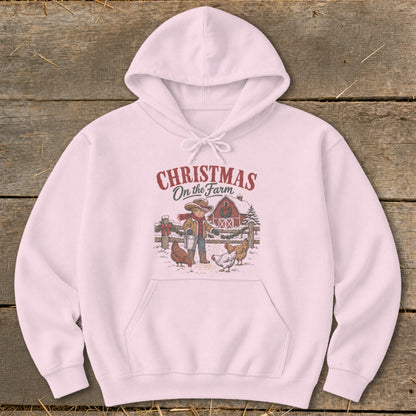 Pink hoodie with a Christmas on the Farm graphic featuring a child feeding chickens.