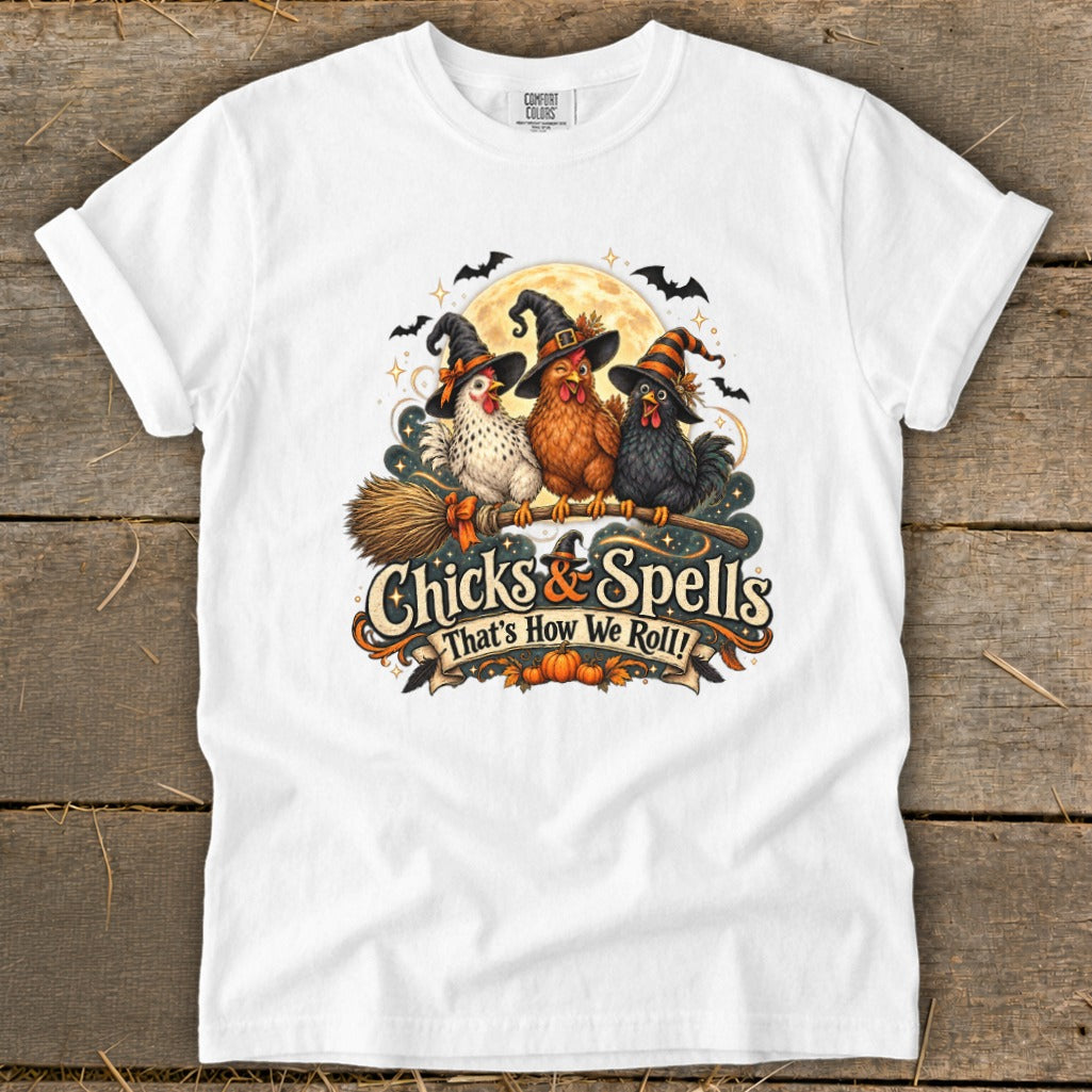 Three Halloween-themed chickens wearing witch hats ride a broomstick with the text "Chicks & Spells".