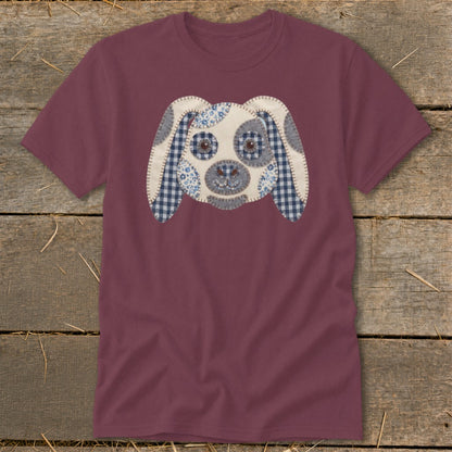 Maroon t-shirt with a fabric applique dog face featuring blue gingham and floral patterns.