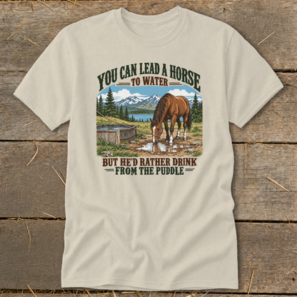 Light-colored t-shirt featuring a graphic of a horse drinking from a puddle with humorous text.