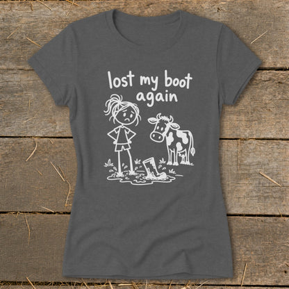 A dark gray t-shirt featuring a white graphic of a girl, a cow, and a boot stuck in mud with text saying lost my boot again.