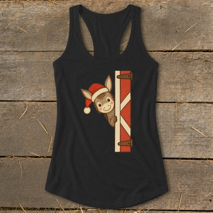 Donkey wearing Santa hat peeking from behind barn door.