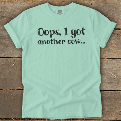 Light blue t-shirt with black text "Oops, I got another cow..."